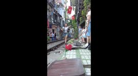 Shopkeeper ushers tourists away from tracks at Train Street in Hanoi