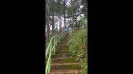 Tourist has fun trying to slide down mountain steps handrail