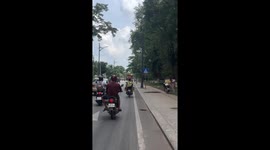 Motorcycle rider balances plastic stools on his head