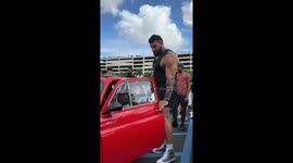 Giant 6 foot 10 bodybuilder's head pokes out sunroof as he squeezes into tiny car