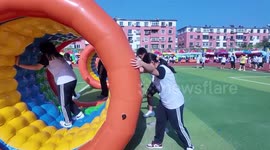 Students roll giant inflatable with classmate tumbling inside