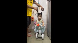 Father washes daughter’s hair while she rides toy bike in Guangdong, China