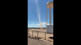 Dust devil forms near water tower in San Simon, Arizona, USA