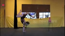 Contortionist fires bow-and-arrow while doing a handstand
