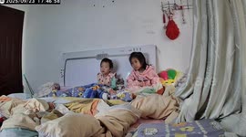 Affectionate kitten watches cartoon on bed with toddlers