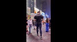 A 6’10” “SECURITY” giant walks through Times Square, making everyone else look like action-figures in his city.