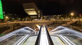 Night time timelpase of the glories park and metro station with the torre agbar skyscraper lit up at night in barcelona, spain