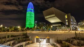 Night time timelpase of the glories park and metro station with the torre agbar skyscraper lit up at night in barcelona, spain