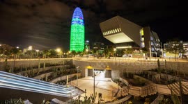 Night time timelpase of the glories park and metro station with the torre agbar skyscraper lit up at night in barcelona, spain