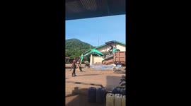 Excavator uses its bucket to climb down from lorry