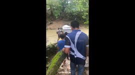 Neighbours work together to carry a coffin across a flooded bridge