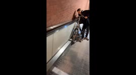 Man loses balance and tumbles with bicycle on flat escalator in Tilburg, Netherlands