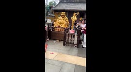 Tourist does his scratch cards in front of Buddha statue for good luck