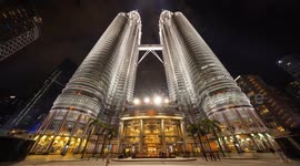 The petronas twin towers in kuala Lumpur lit up at night with crowds of people on the streets below