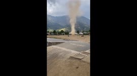 Fearless school children play in dust devil tornado tearing through field
