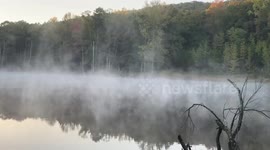 Mist drifts over a pond on a cool autumn morning in Ferndale, Arkansas, USA