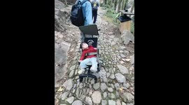Child endures bumpy stroller ride on rocky path in Zhejiang, China
