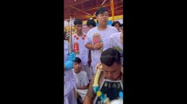 Devotee has cheeks pierced with bamboo umbrellas at festival in Thailand