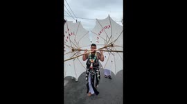 Devotee has cheeks pierced with bamboo umbrellas at festival in Thailand
