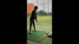 Novice golfer whacks basket of balls at driving range