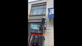 Worker rescues cat stranded on a second-floor windowsill