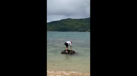 Friend slips into water while posing on rocks in Phuket, Thailand