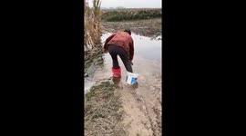 Woman struggles to cross muddy swamp using buckets in Henan, China