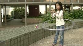 Girl solves Rubik's Cube while hula hooping