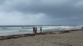 People gather on Florida beach to film and photograph approaching hurricane