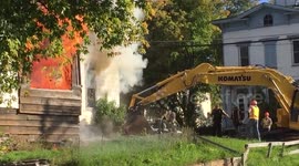 Construction workers use excavator to rescue man from burning building