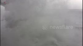 Massive waves crash against sea wall and spill onto promenade