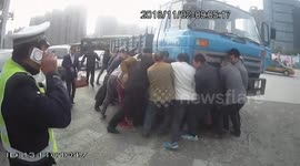 A group of people lift up lorry to rescue two people trapped under it