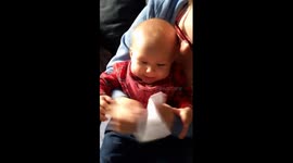 Cute baby laughs hysterically at some paper