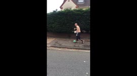 Topless man with beer plays football on road