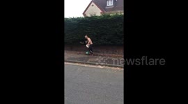 Newsflare Edit - Topless man with beer plays football on road