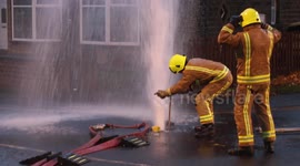 Firemen stop a burst pipe that feeds the hose's - motorist drove into it.