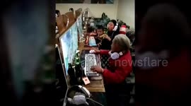 Grandma plays computer games with family in internet cafe