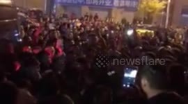 Thousands of onlookers watch a woman smashing mistress's shop