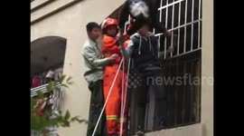 Firefighters rescue an elderly man falling and hanging on the laundry rack on second floor