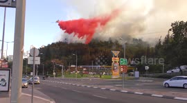 Airplane drops fire retardant on a forest near gas station in Haifa, Israel.