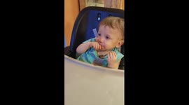 Sleepy baby tries desperately to finish chocolate bar