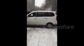 Car slips on snowy road and gets stuck between two walls