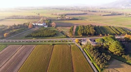 Aerial shot, foggy fields, an ancient roman aqueduct and cars driving behind it, filmed with drone