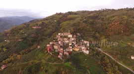 Aerial shot, gorgeous small village on the hill flyover, in middle of the fall colors, filmed with drone
