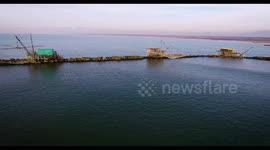 Some fishermen houses, a coast and a boat going fast, in Tuscany, Italy, filmed with drone