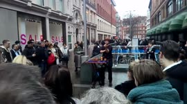 A busker entertains shopping with magic at the front of Harrods