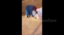 Elderly woman crushes ice frozen on road near a pedestrian crossing