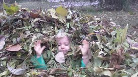 Nature loving toddler plays in pile of leaves