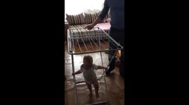 Nine-month-old baby takes her first steps with assistance of metal clothes dryer