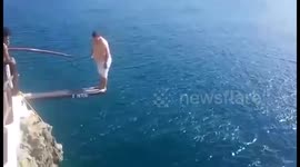 Man attempts an ambitious cliff jump, belly flops badly